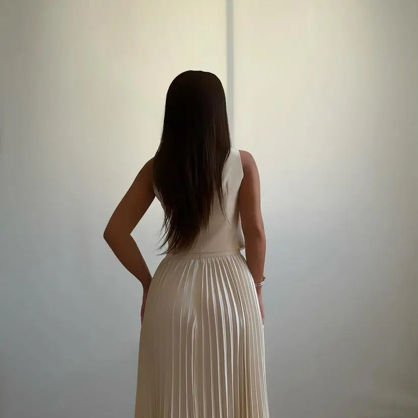 Off-white two-piece set with pleated skirt and sleeveless buttoned top