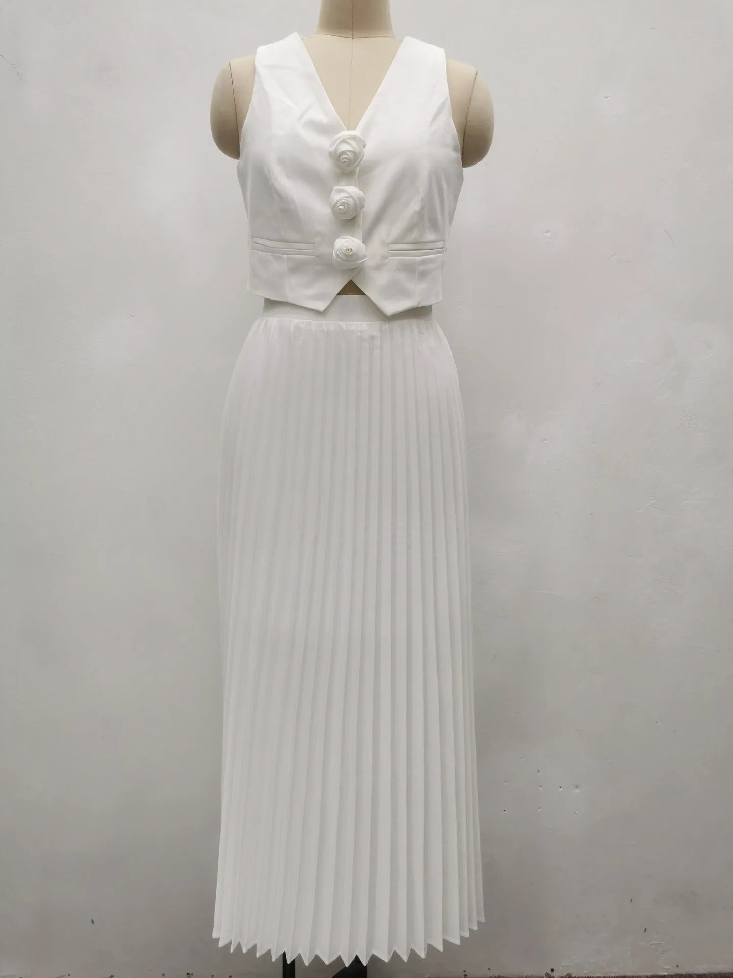 Off-white two-piece set with pleated skirt and sleeveless buttoned top